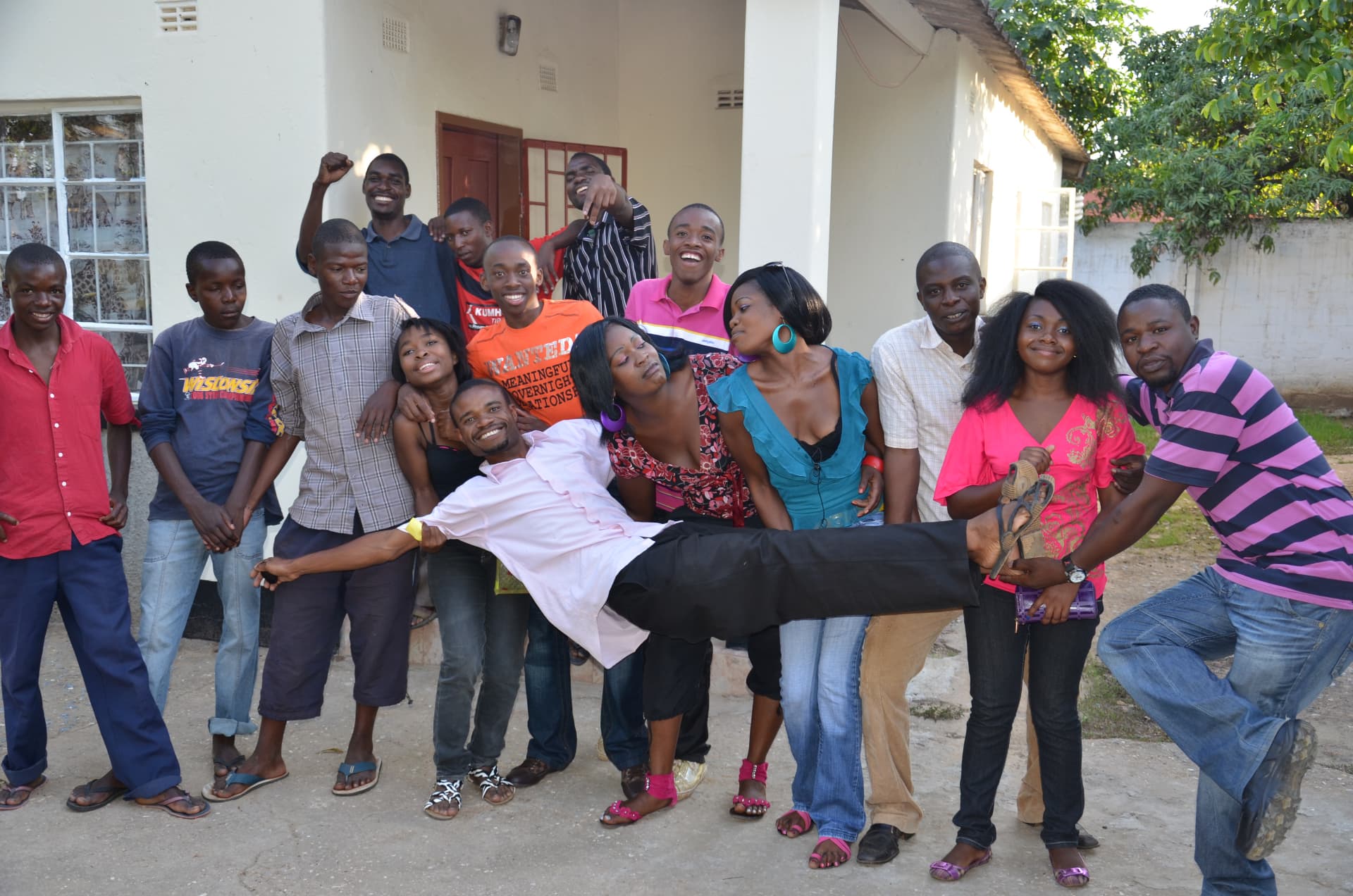 A cheerful group of young people outside a house